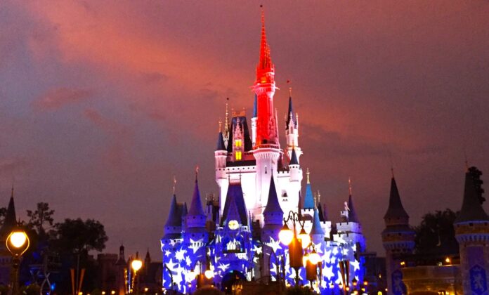 Nighttime view of Cinderella Castle with red, white, and blue lighting.